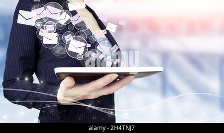 Sending email.Bulk mail. Hand hold white tablet with digital hologram Email and sms sign on light blurred background. Email and sms marketing concept Stock Photo