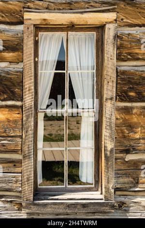 Old weathered wood window with a curtain in rustic log cabin Stock Photo