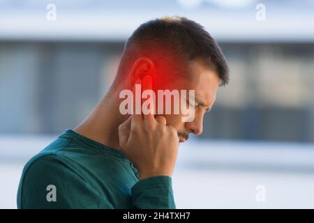 Man suffering because of strong earache or ear pain. Otitis Stock Photo