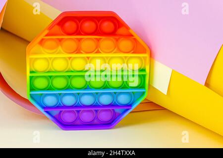 Trendy simple dimple or pop it sensory toy for kids on bright paper background. Popular antistress silicone children bubble fidget in rainbow colors. Stock Photo