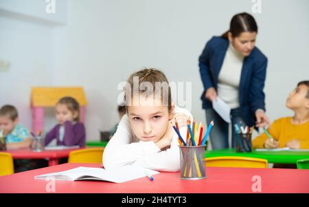 Sad schoolgirl in classroom during lesson Stock Photo