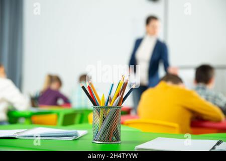 Pencils and notebooks on blurred background of elementary school students Stock Photo