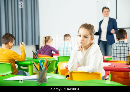 Portrait of tired schoolgirl sitting in classroom elementary school Stock Photo