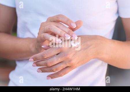 Hands skin care. Woman applying moisturizer or hand cream on her dry hands. Skin protection Stock Photo