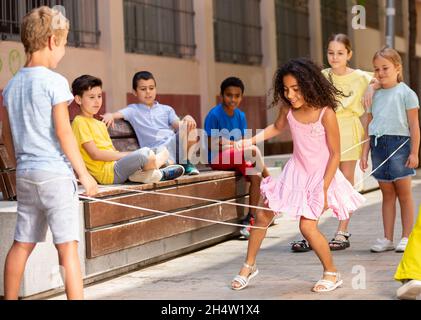 Mexican girl playing rubber band jumping game with european friends Stock Photo