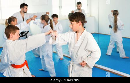 Teenagers practicing new karate moves in pairs in class Stock Photo