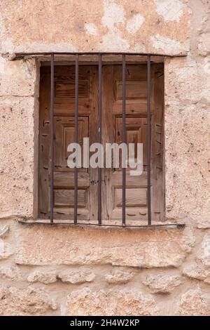 Old wooden window with rusty bars in the stone walls of a village Stock Photo