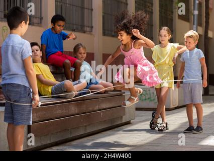 Mexican girl playing rubber band jumping game with european friends Stock Photo