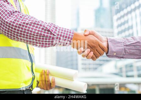 Civil engineer shaking hands with businessman on  urban city background. Stock Photo