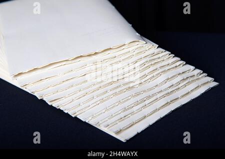 The process of book binding; putting together raw paper folders. Black background Stock Photo