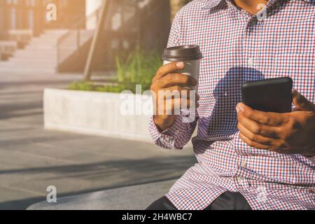 Close up hand man holding coffee paper cup and smartphone. Stock Photo
