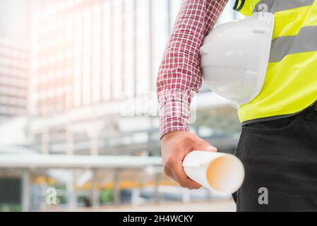 Engineering holding safety helmet on building background. Stock Photo