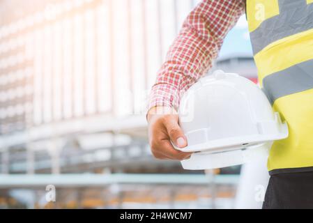 Engineering holding safety helmet on building background. Stock Photo