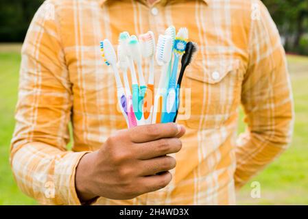 Man holding Old colorful toothbrushes on nature background Stock Photo