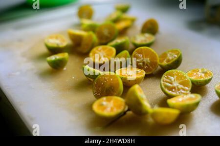 Sri Lankan variety of mandarin oranges unpeeled and cut into halves and scattered in a cutting board ready for making a fresh juice. Rich in vitamins. Stock Photo
