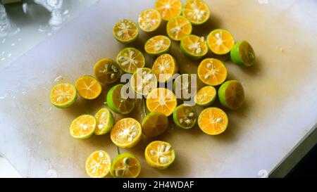 Sri Lankan variety of mandarin oranges unpeeled and cut into halves and scattered in a cutting board ready for making a fresh juice. Rich in vitamins. Stock Photo