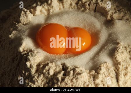 Close up of two orange yolks of eggs in the middle of white flour, cooling process Stock Photo