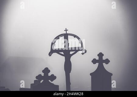 Misty view of dark stone crosses and tombstones in a deserted graveyard. Halloween concept Stock Photo