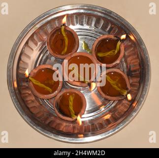 Ignited Multiple Diyas or mud oil lamps kept on a steel plate during Diwali also called festival of light Stock Photo