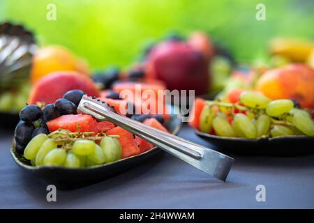 Fruit mix. Peach, grapes, apple, watermelon, melon. Pieces of fruit on a plate on a dark background. Natural food  concept Stock Photo