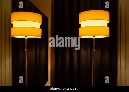 Room lamp with round lampshade and metal legs. A modern looking lamp used to create ambiance indoors. With its reflection in the mirror. Stock Photo