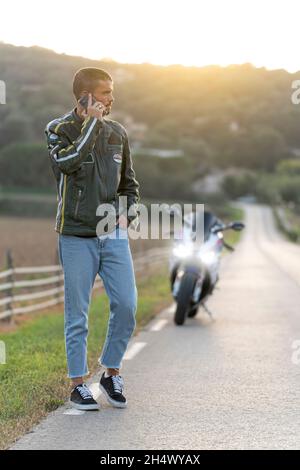 Young man with motorcycle breakdown on the road talking on the phone Stock Photo