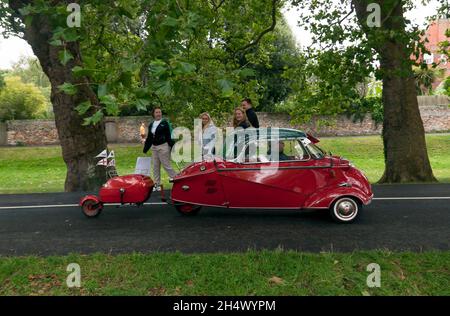 Spectators watching  a Red, 1961,  Messerschmitt KR200,  with matching trailer,  leaving the show ground  at the end of the Sandwich Festival Classic Car Show 2021 Stock Photo