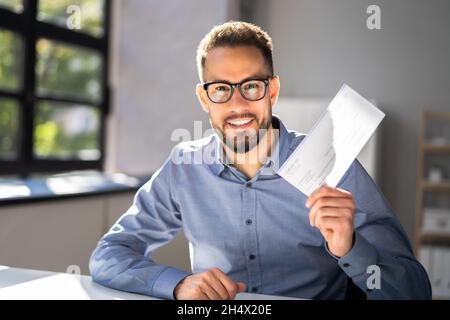 Holding Paycheck Or Payroll Check Or Insurance Cheque In Hand Stock Photo