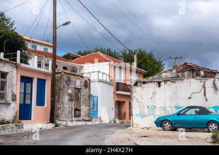 Scenic distant Greek traditional village narrow streets on Lefkada island, Greece. Weathered local atmosphere with small colored houses and a car with Stock Photo