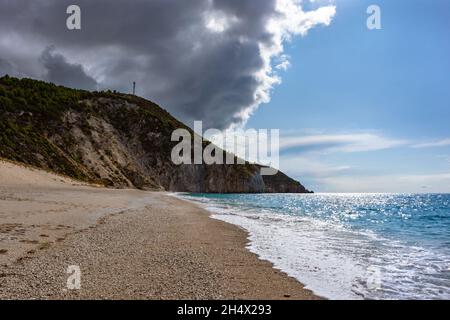 Stormy clouds above Mylos beach shore on sunny coast with high cliffs and blue seascape. Lefkada island in Greece. Summer travel to Ionian Sea Stock Photo