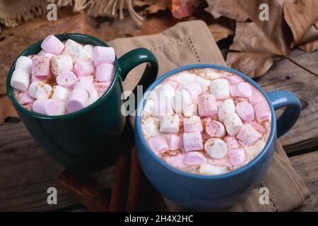 Pink and white marshmallows with hot chocolate drink filled in mugs on table at cafe Stock Photo
