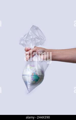 Global Warming and Climate Change concepts. Woman hand holds a glove in plastic bag. Environmental conservation. World globe in a plastic bag Stock Photo