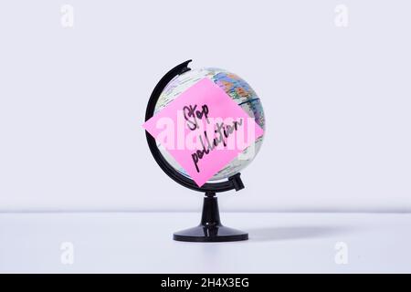 The Earth globe with a sticker and note - stop pollution. Concept of ecology and stop plastic Stock Photo