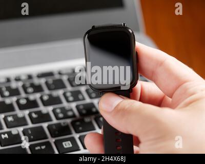 Male hand checking smartwatch keyboard of his laptop computer. Man working on laptop at a desk Stock Photo