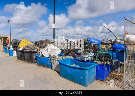 Plastic tubs of rope and fishing net and Lobster Crab and Prawn pots stacked on the quay at the working harbour in Newequay on the North Cornwall coas Stock Photo