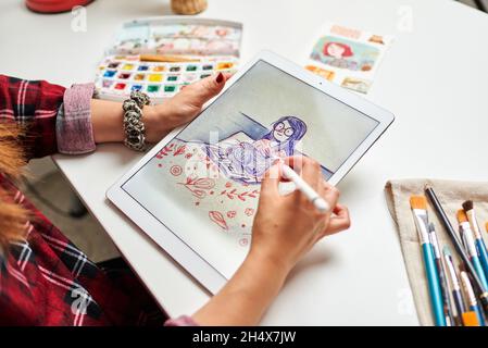 Caucasian female artist illustrator painting drawing on touch digital tablet with stylus Stock Photo