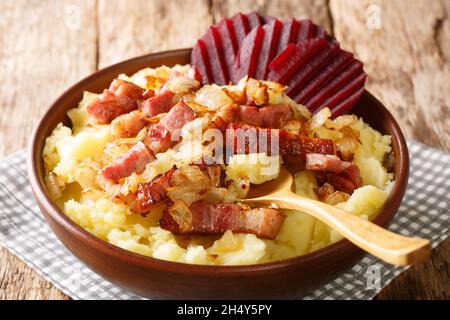 Danish dish Burning Love consists of mashed potatoes topped with an onion and bacon close-up in a plate on the table. Horizontal Stock Photo