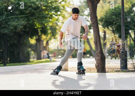 Man skating with inline skates in a paved path of a park Stock Photo