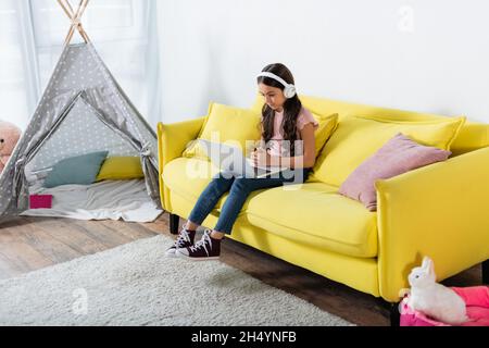 preteen girl in wireless headphones studying online at home Stock Photo