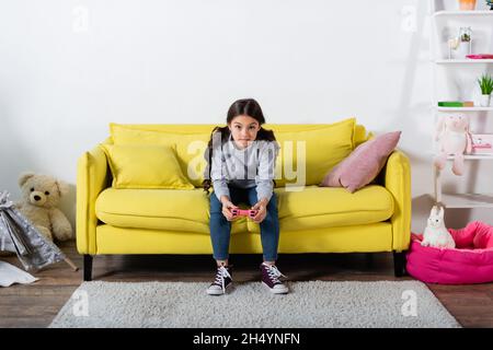 KYIV, UKRAINE - SEPTEMBER 17, 2021: tensed preteen kid playing video game at home Stock Photo