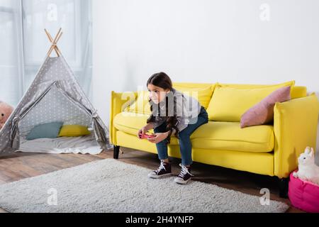 KYIV, UKRAINE - SEPTEMBER 17, 2021: worried preteen girl playing video game at home Stock Photo