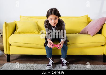 KYIV, UKRAINE - SEPTEMBER 17, 2021: tensed preteen girl playing video game at home Stock Photo