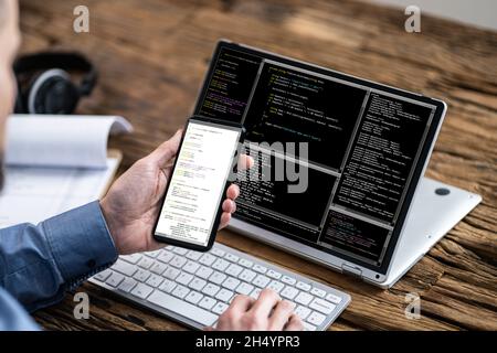 Programmer Coding On Laptop And Smartphone. Mobile Developer Stock Photo