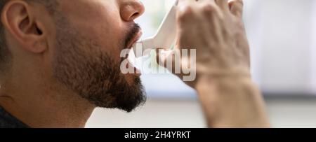 Man With Asthma Using An Asthma Inhaler For Preventing Attacks Stock Photo