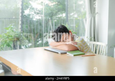 Boy fell asleep in class, tired, bored at school on online learning Stock Photo