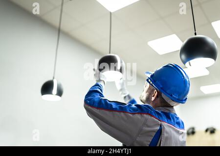 Home Ceiling Light Equipment Maintenance. Professional Electrician Worker Stock Photo