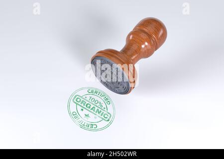 Green superior quality stamp with wooden rubber stamper isolated on white background with text certified 100% Organic . Stock Photo