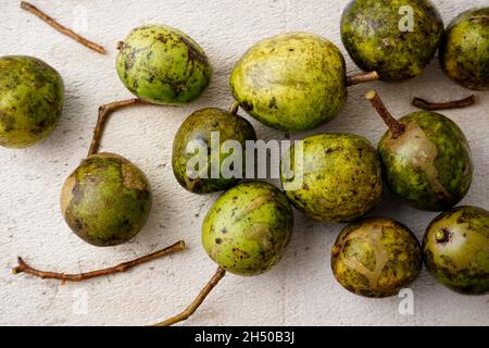 June plum, Spondias dulcis, or ambarella edible fruit on white cement plate background. Good source of Vitamins and natural antioxidants. Stock Photo