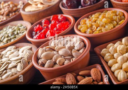 Different nuts seeds and dried fruits in bowls on kitchen table Stock Photo