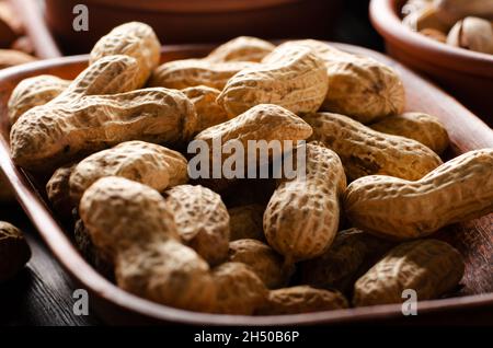 Peanuts in clay bowl on kitchen wooden table food background Stock Photo
